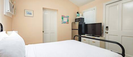 Un dormitorio con cama, televisión, microondas y una puerta.