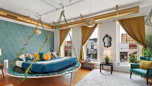 Ein Schlafzimmer mit einem Hängebett, Blick auf die Stadt und einem grünen Sofa.