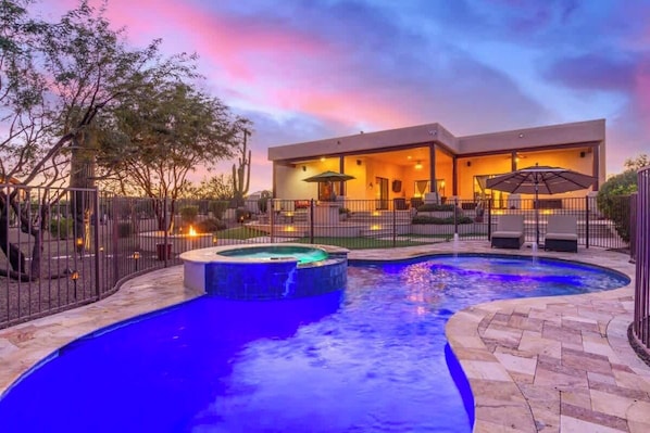 A modern house with a swimming pool, outdoor seating, and a well-lit patio area.