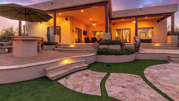 Une maison moderne dotée d’un patio, d’un espace salon extérieur et d’un intérieur bien éclairé.