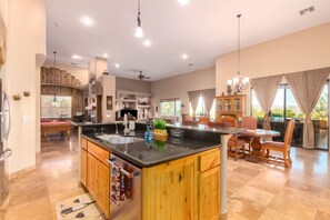 A spacious kitchen with a central island, wooden cabinets, and a dining area with chairs and a table.