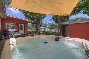 Un bain à remous doté d’un auvent jaune, entouré d’une terrasse et de mobilier d’extérieur.