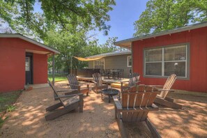 A red building with a patio area featuring wooden chairs and a table.