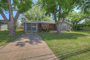 A single-story house with a garage, surrounded by trees and a well-maintained lawn.