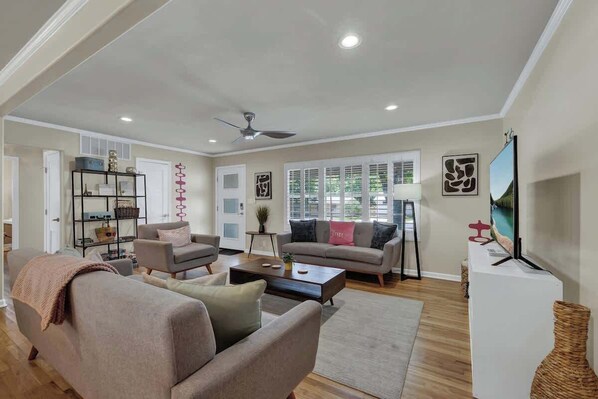 A spacious living room with a ceiling fan, a television, and a bookshelf.