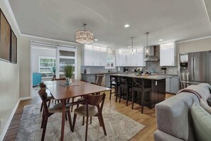 A modern kitchen with a dining area, a large island, and a built-in oven.