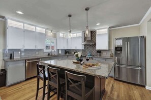A modern kitchen with white cabinets, stainless steel appliances, and a central island with bar stools.