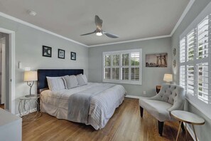 A bedroom with a bed, a chair, a window, and a ceiling fan.
