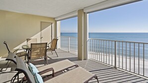 A balcony with a view of the beach, furnished with chairs and a table. - White Caps 1202 by Liquid Life (Orange Beach)