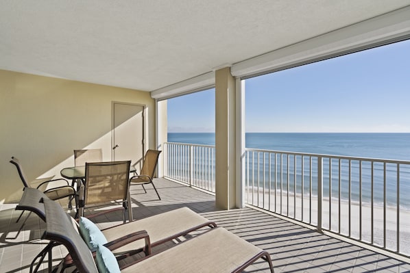 A balcony with a view of the beach, furnished with chairs and a table. - White Caps 1202 by Liquid Life (Orange Beach)