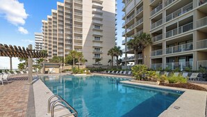 A swimming pool with lounge chairs and a pergola, surrounded by tall residential buildings. - White Caps 1202 by Liquid Life (Orange Beach)