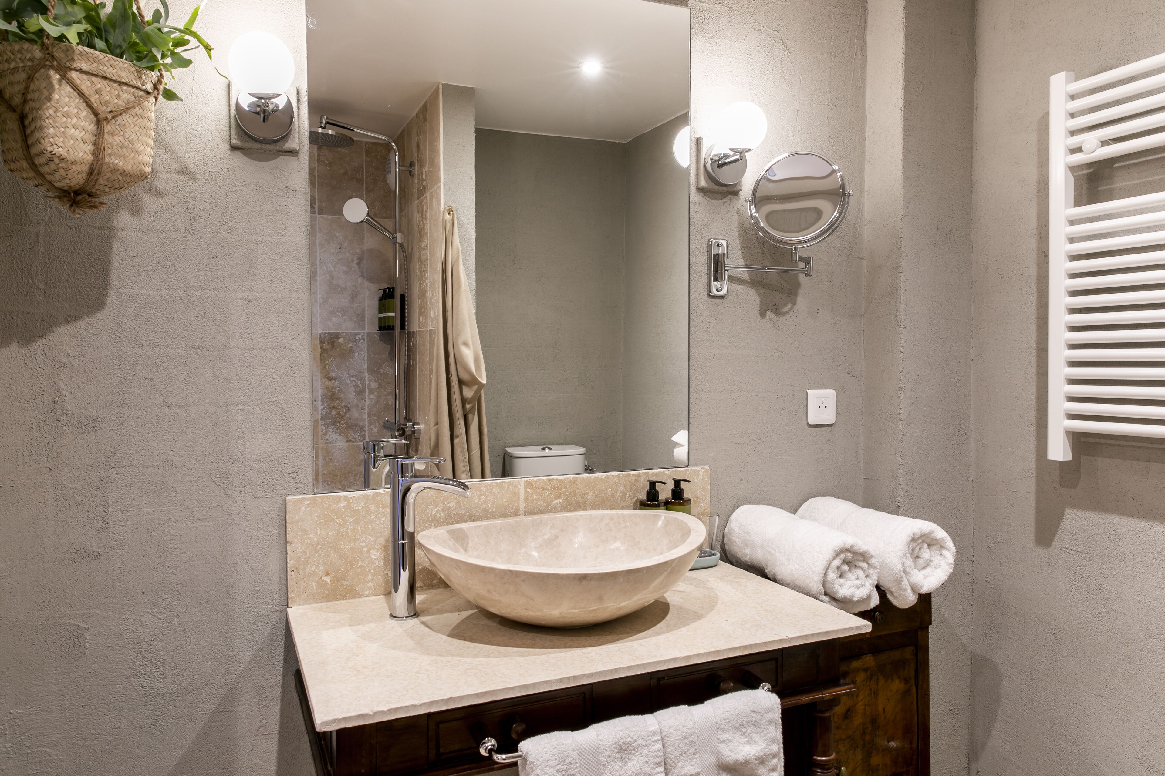 Un baño con un lavamanos de pedestal grande, un espejo, un perchero y una planta colgante.