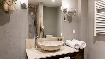 Un baño con un lavamanos de pedestal grande, un espejo, un perchero y una planta colgante.
