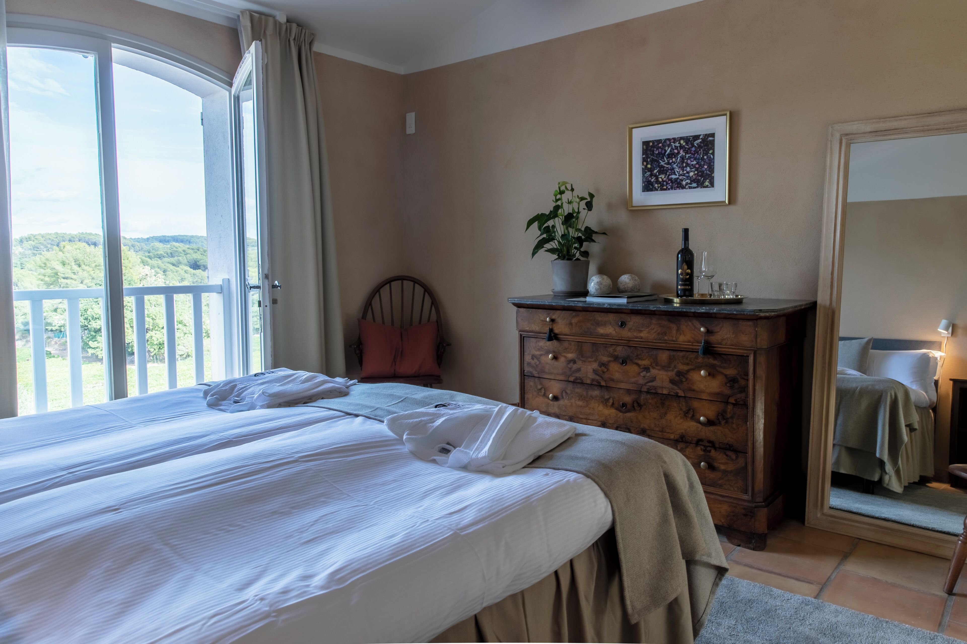 Une chambre à coucher avec un grand lit, une commode, un miroir et une plante en pot.