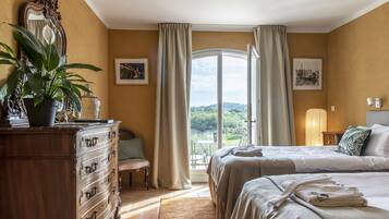 Un dormitorio con dos camas, un aparador, una silla y un ventanal con cortinas.