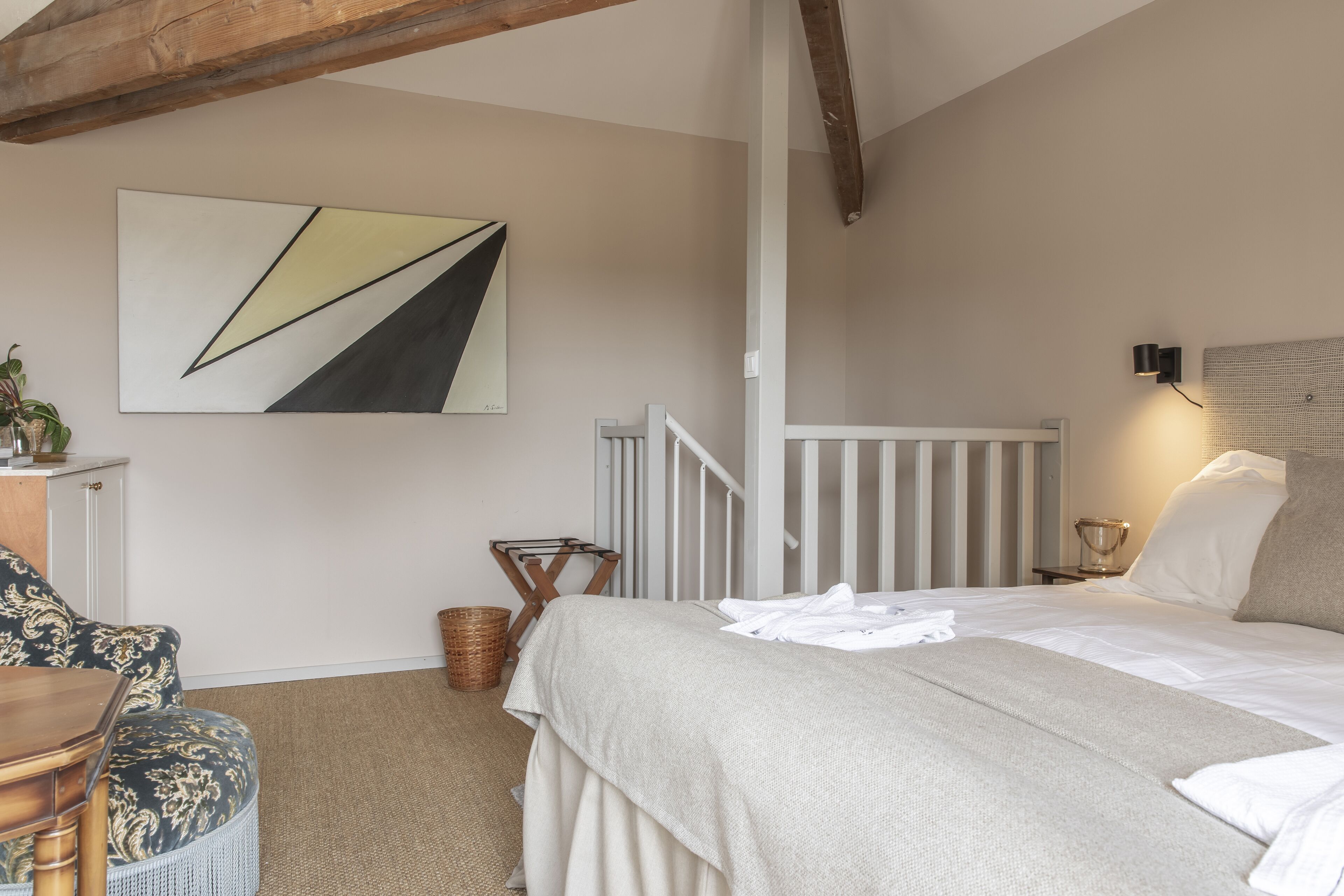 Une chambre à coucher avec un lit, une chaise, un tableau et une lampe.