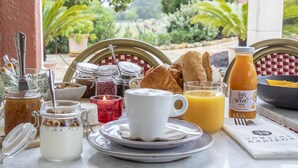 Une table de petit-déjeuner avec divers aliments, un verre de jus d’orange et une bouteille de jus.