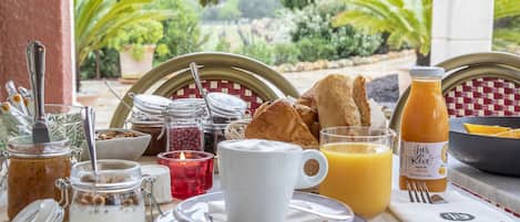 A breakfast table with various food items, a glass of orange juice, and a bottle of juice.