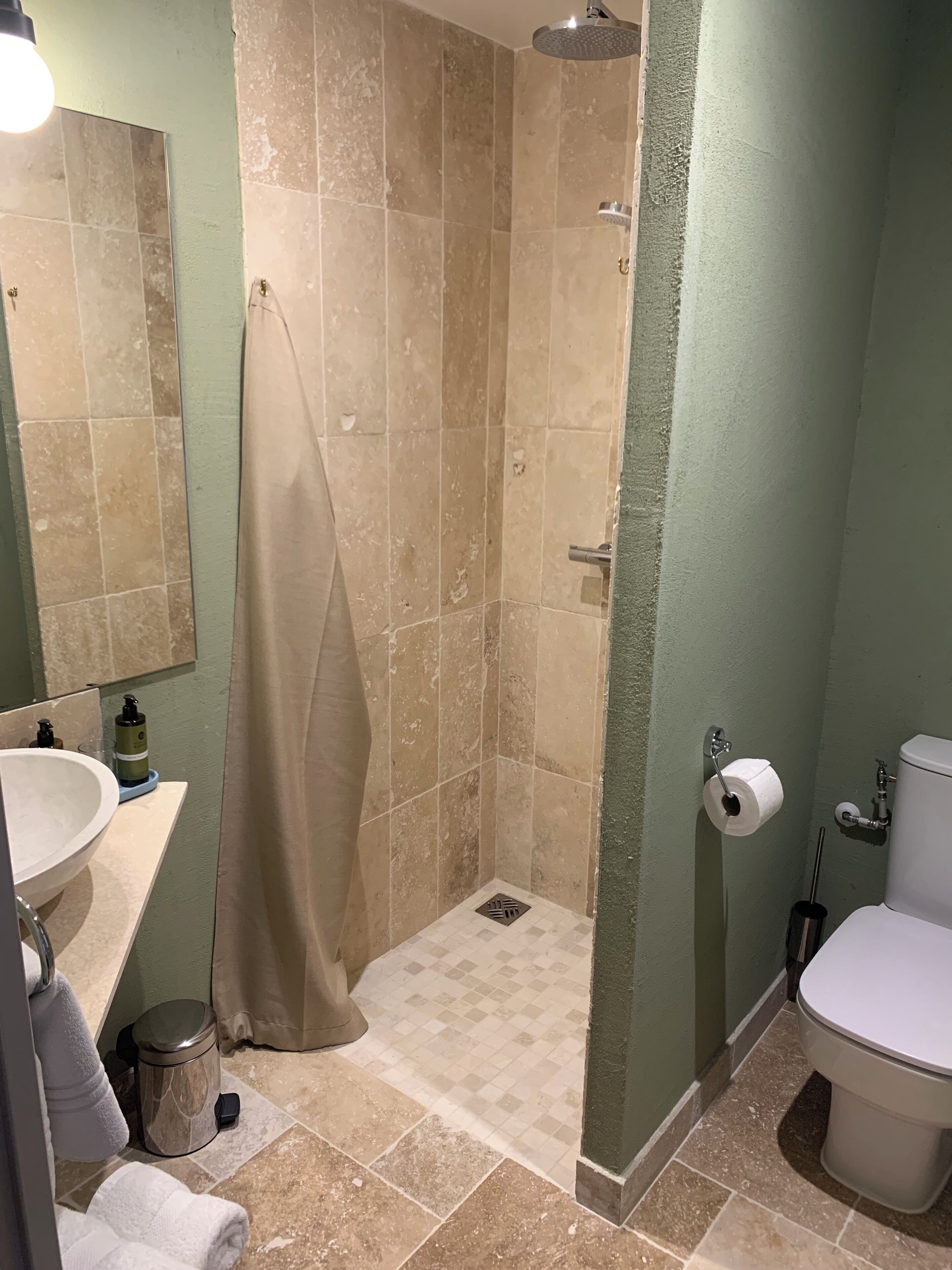 Une salle de bain équipée d’une douche, de toilettes, d’un lavabo et d’un miroir.