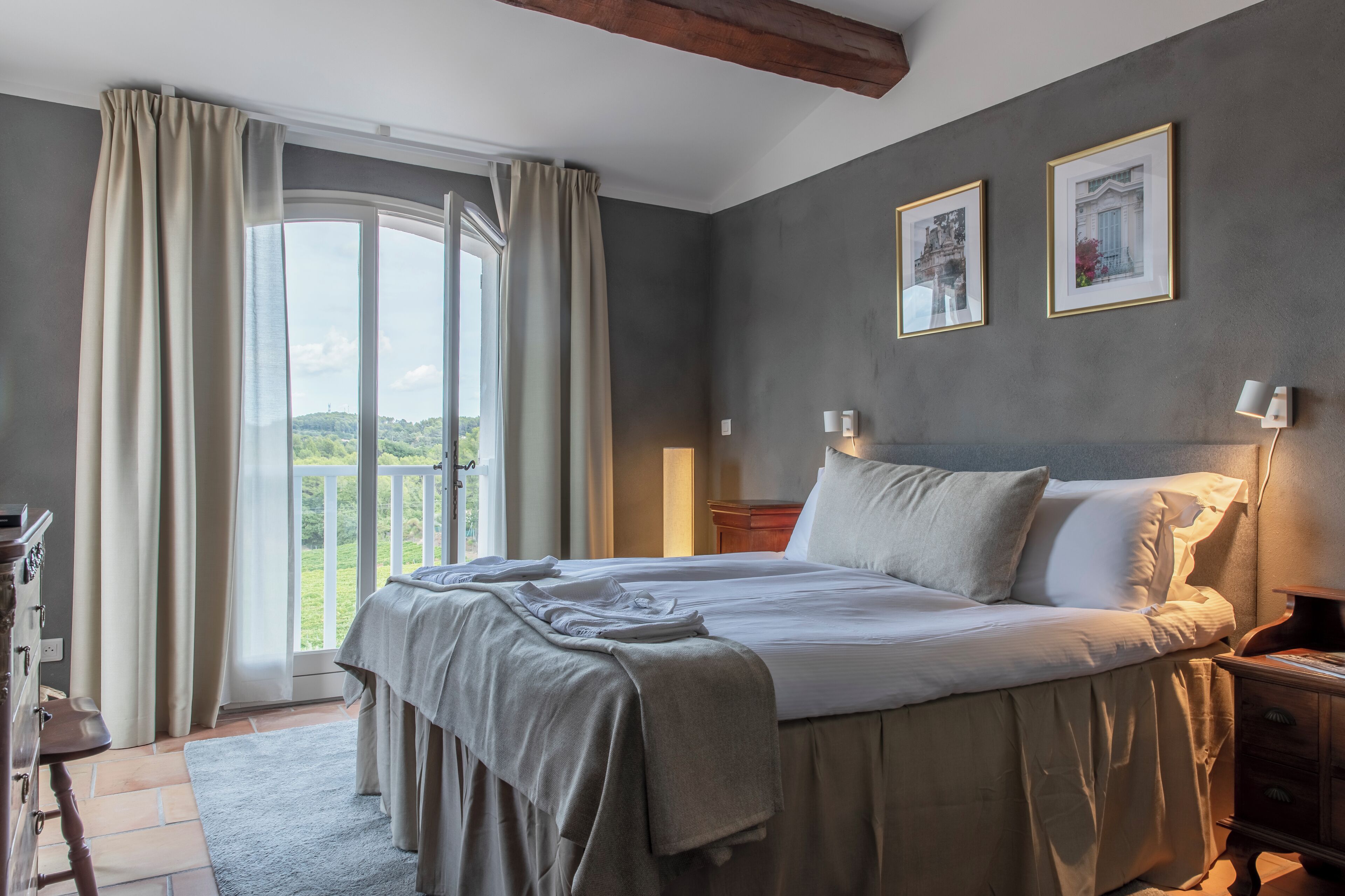 Ein Schlafzimmer mit einem großen Bett, einem Nachttisch, einer Kommode und Blick auf einen Balkon.