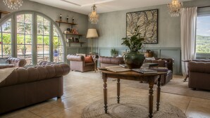 Un salon spacieux doté d’une grande fenêtre en arc de cercle, de canapés en cuir, d’une table basse en bois et d’un éclairage décoratif.