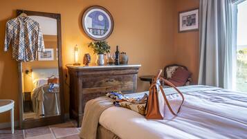 Une chambre d’hôtel avec un lit, une commode, un miroir, une table de chevet et une fenêtre avec des rideaux.