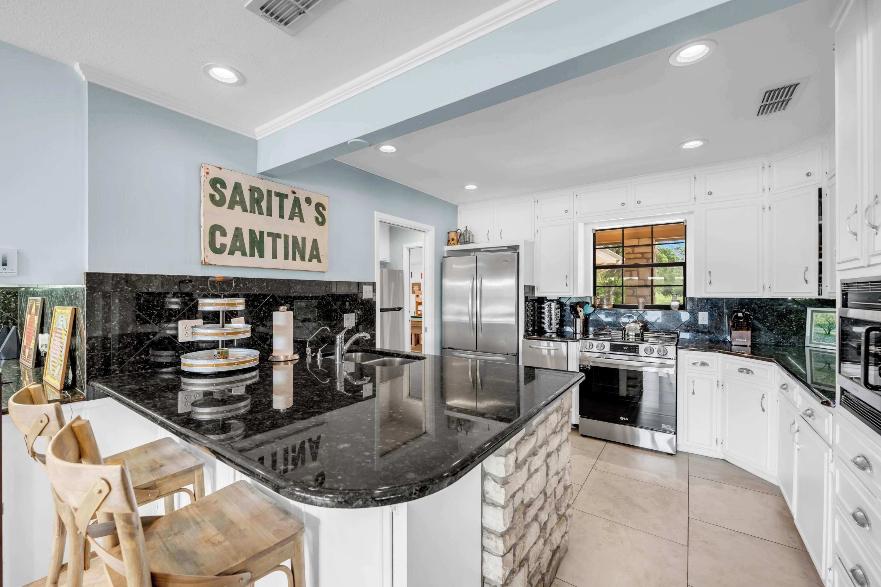 A modern kitchen with a black granite countertop, stainless steel appliances, and white cabinetry.