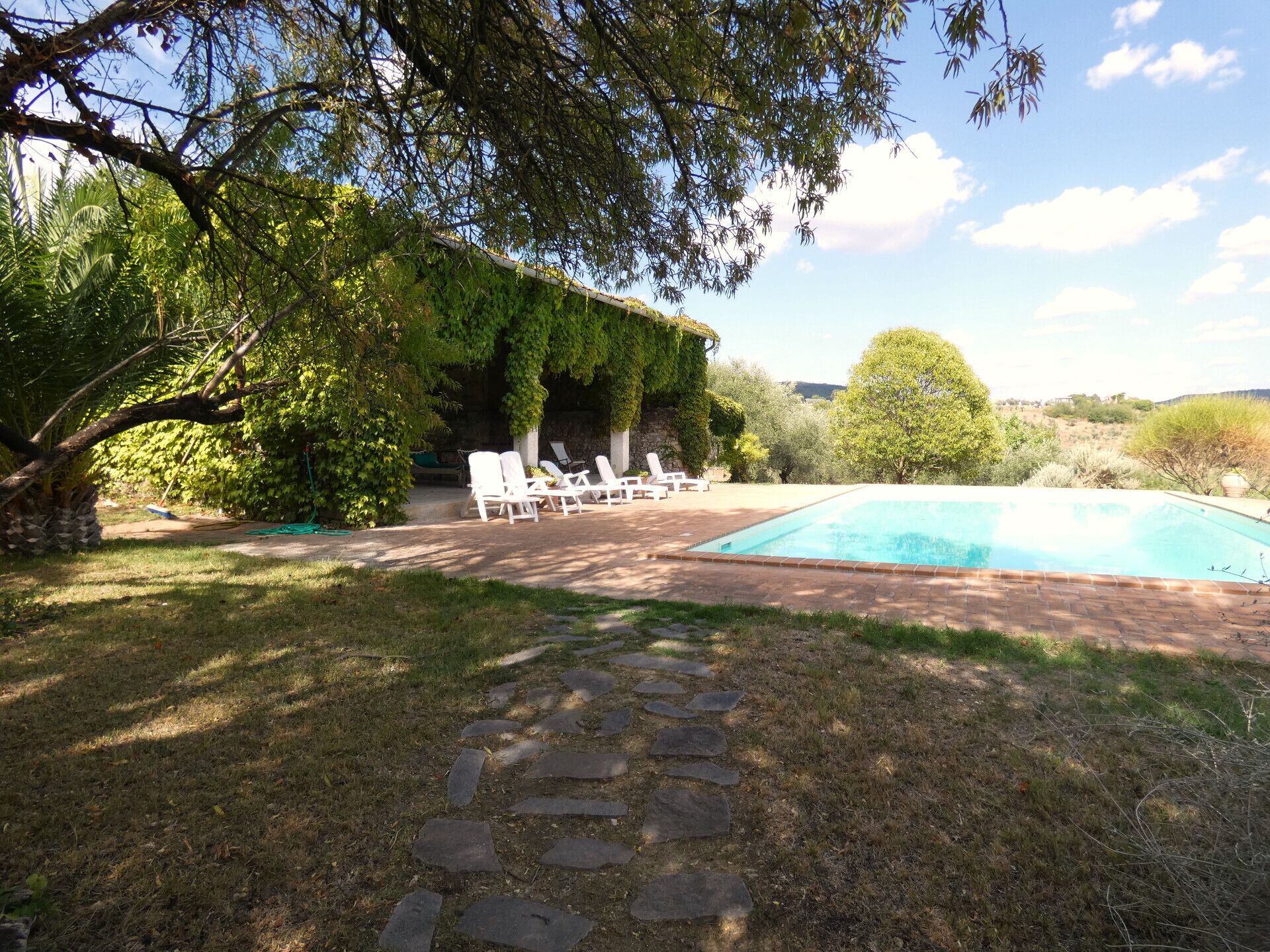 A backyard with a swimming pool, stone pathway, and outdoor seating area.