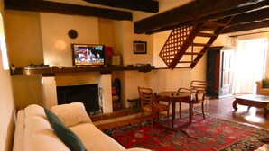 Ein gemütliches Wohnzimmer mit Kamin, Fernseher, Essbereich mit Stühlen und einer Treppe.