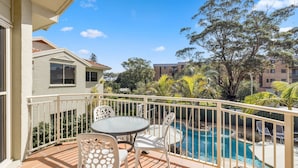 Ein Balkon mit Pool, Gartenmöbeln und umliegendem Grün.