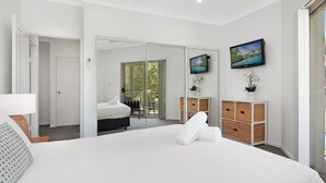 Ein modernes Hotelzimmer mit einem großen Bett, einem Balkon mit Aussicht, einem Fernseher und einer Minibar.