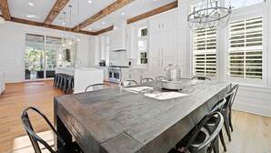 A spacious kitchen with a large wooden table, white cabinets, and a chandelier. - Private Neighborhood beach access, large pool, golf cart, walk to beach/dine (Santa Rosa Beach)
