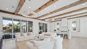 A spacious living area with white furniture, a glass coffee table, and a wooden ceiling. - Private Neighborhood beach access, large pool, golf cart, walk to beach/dine (Santa Rosa Beach)