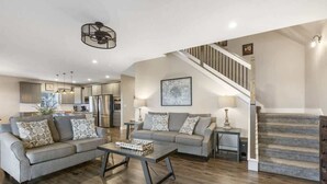 A modern living room with a sofa, coffee table, and a staircase leading to an upper level. - Stillwater - Indoor pool & lake views (Branson)