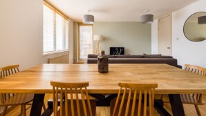 A spacious dining area with a wooden table and chairs, a sofa, and a lamp. - The Clerkenwell Apartments. (London)