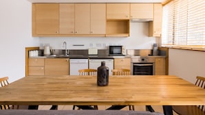A modern kitchen with wooden cabinets, stainless steel appliances, and a wooden dining table. - The Clerkenwell Apartments. (London)