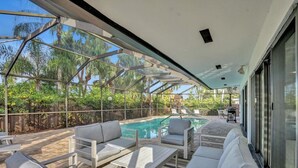A modern outdoor pool area with glass walls, lounge chairs, and a view of palm trees. - Modern Luxe Design, 4K SF  Pool 5 Min to Beach (Hollywood)