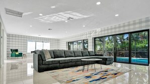 A modern living room with a grey sectional sofa, a small round coffee table, and a colorful rug. - Modern Luxe Design, 4K SF  Pool 5 Min to Beach (Hollywood)
