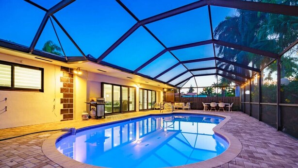A covered swimming pool with a brick floor, a grill, and a patio area with chairs and tables. - Modern Luxe Design, 4K SF  Pool 5 Min to Beach (Hollywood)