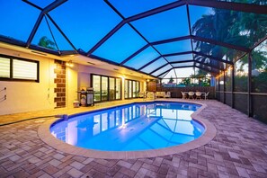 A covered swimming pool with a brick floor, a grill, and a patio area with chairs and tables. - Modern Luxe Design, 4K SF  Pool 5 Min to Beach (Hollywood)
