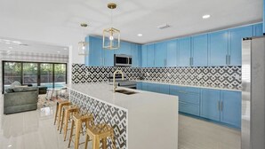 A modern kitchen with blue cabinets, a white island, and a patterned backsplash. - Modern Luxe Design, 4K SF  Pool 5 Min to Beach (Hollywood)