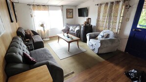 A living room with a sofa, armchairs, a coffee table, and a TV. - BEAUTIFUL APARTMENT IN FRONT OF THE SEA (Portobelo)