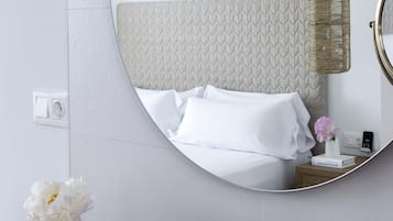 Een badkamer met een ronde spiegel, een gouden kraan en een bed met witte lakens.