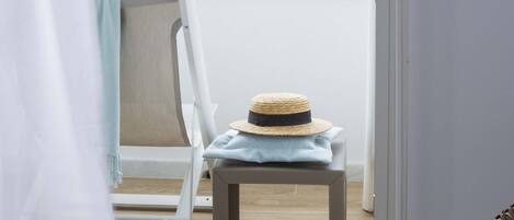 A balcony with a chair, a hat, and a pair of sandals.