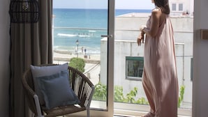 A room with a large sliding glass door leading to a balcony overlooking a beach.