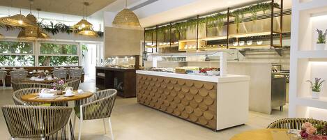 A modern cafe with round tables, wicker chairs, and hanging pendant lights.