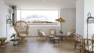 Una habitación amplia con muebles de mimbre, un ventanal con vistas y un ventilador de techo.