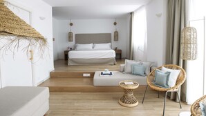 A modern bedroom with a bed, a sofa, and a wicker chair.