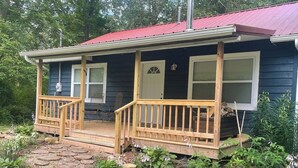 A house with a porch, a red roof, and a garden with a stone pathway.
