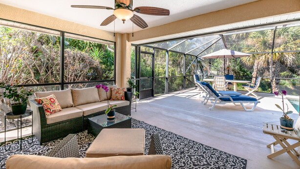 Un vaste espace extérieur aménagé avec un canapé, des fauteuils et un ventilateur de plafond.
